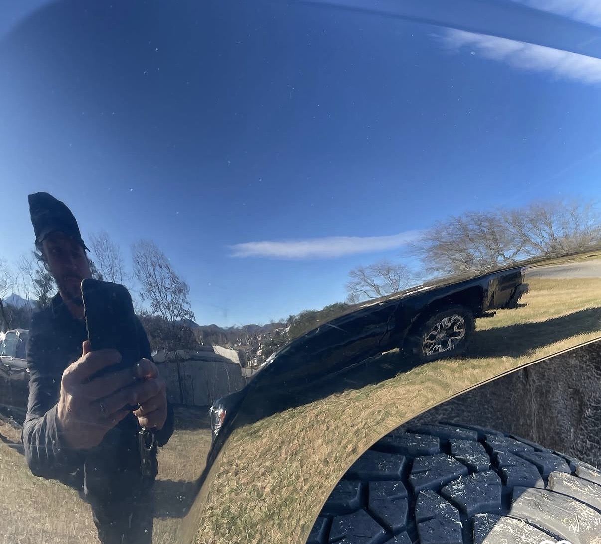 Black pickup truck bedside restored to a smooth mirror finish after paintless dent repair